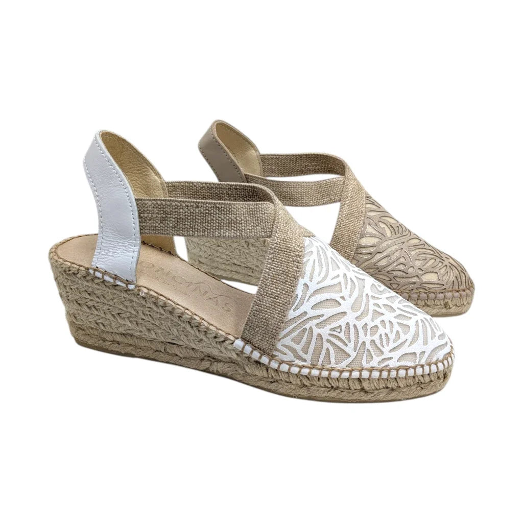 Primer plano de unas cuñas de yute natural. Se aprecia el detalle del grabado láser calado con patrón de hojas en la puntera y la textura de las cintas elásticas laterales para ajuste cómodo.