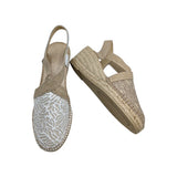 Vista lateral de alpargatas con cuña de esparto Ramoncinas. Muestra la talonera de piel suave en tono nude, la tira elástica del talón y la altura de la suela de yute.