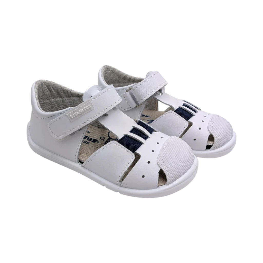 Sandalias infantiles Titanitos modelo Cristian en piel blanca con detalles azules y cierre de velcro.