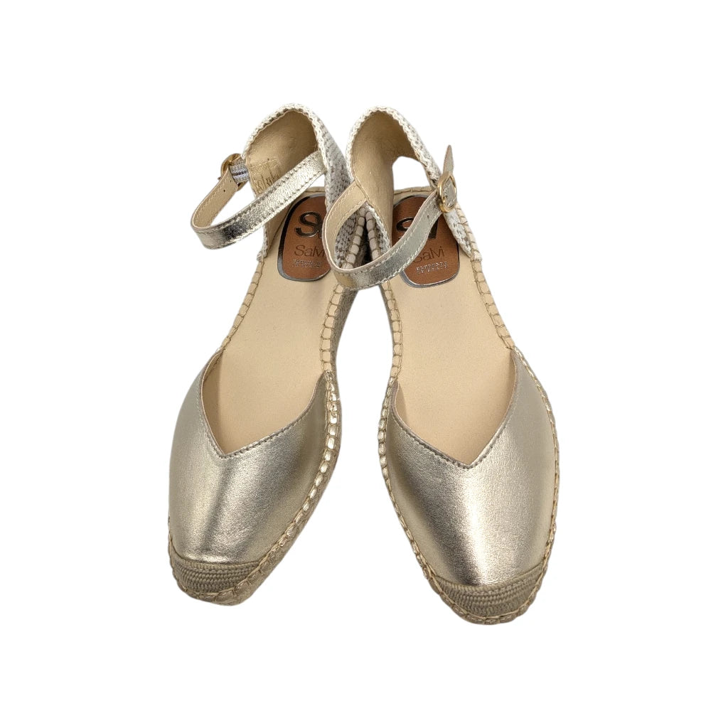 Primer plano de la alpargata y la correa con hebilla dorada de la sandalia Salvi platino.