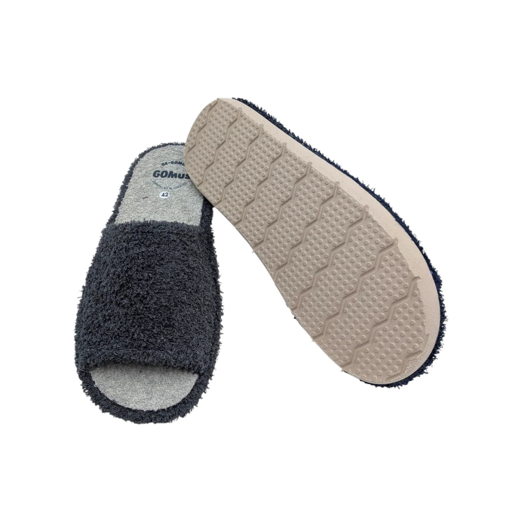 Zapatillas GOMUS de casa con suela de goma blanca ligera y antideslizante. La plantilla es de rizo gris transpirable con el logotipo de la marca visible.