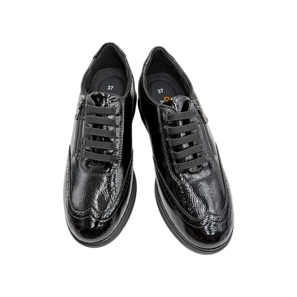 Vista  de frente del zapato y detalles picados tipo brogue en charol negro.